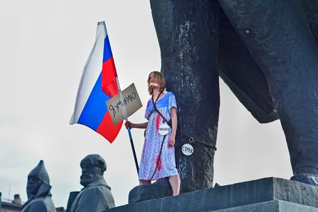 Девушка с триколором приковала себя цепями к памятнику Ленина