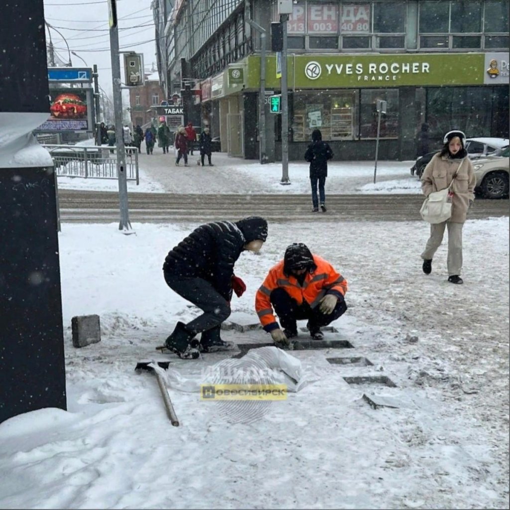 Рабочие кладут плитку в снег около Первомайского сквера